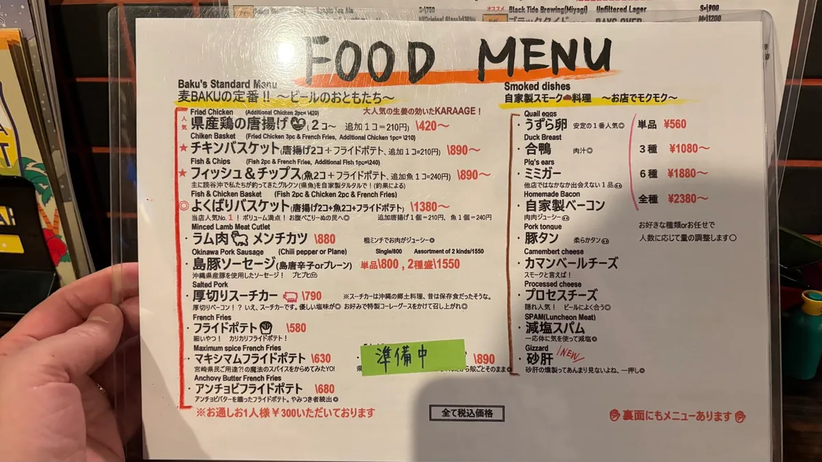 A laminated food menu headed FOOD MENU in hand lettering, with a left column of fried dishes and a right column of smoked dishes, the dish names given in English above the Japanese