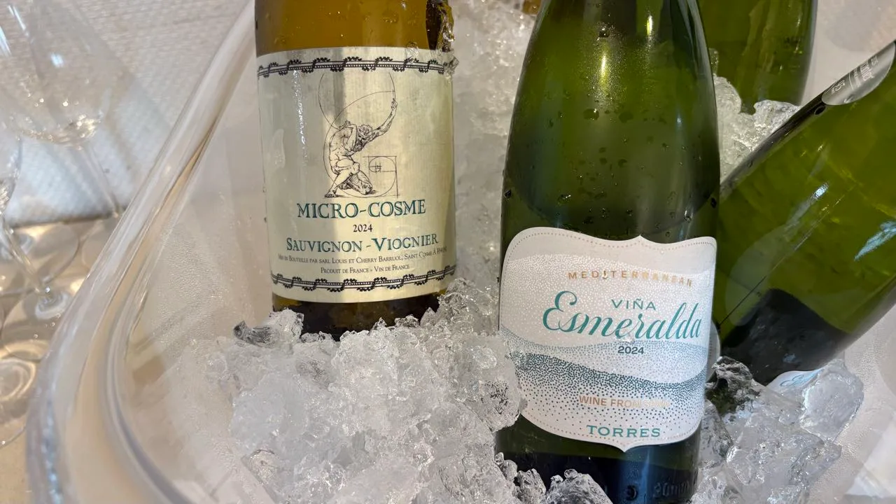 Two open white wine bottles standing in crushed ice, one labelled MICRO-COSME 2024 Sauvignon-Viognier and one Viña Esmeralda 2024 by Torres