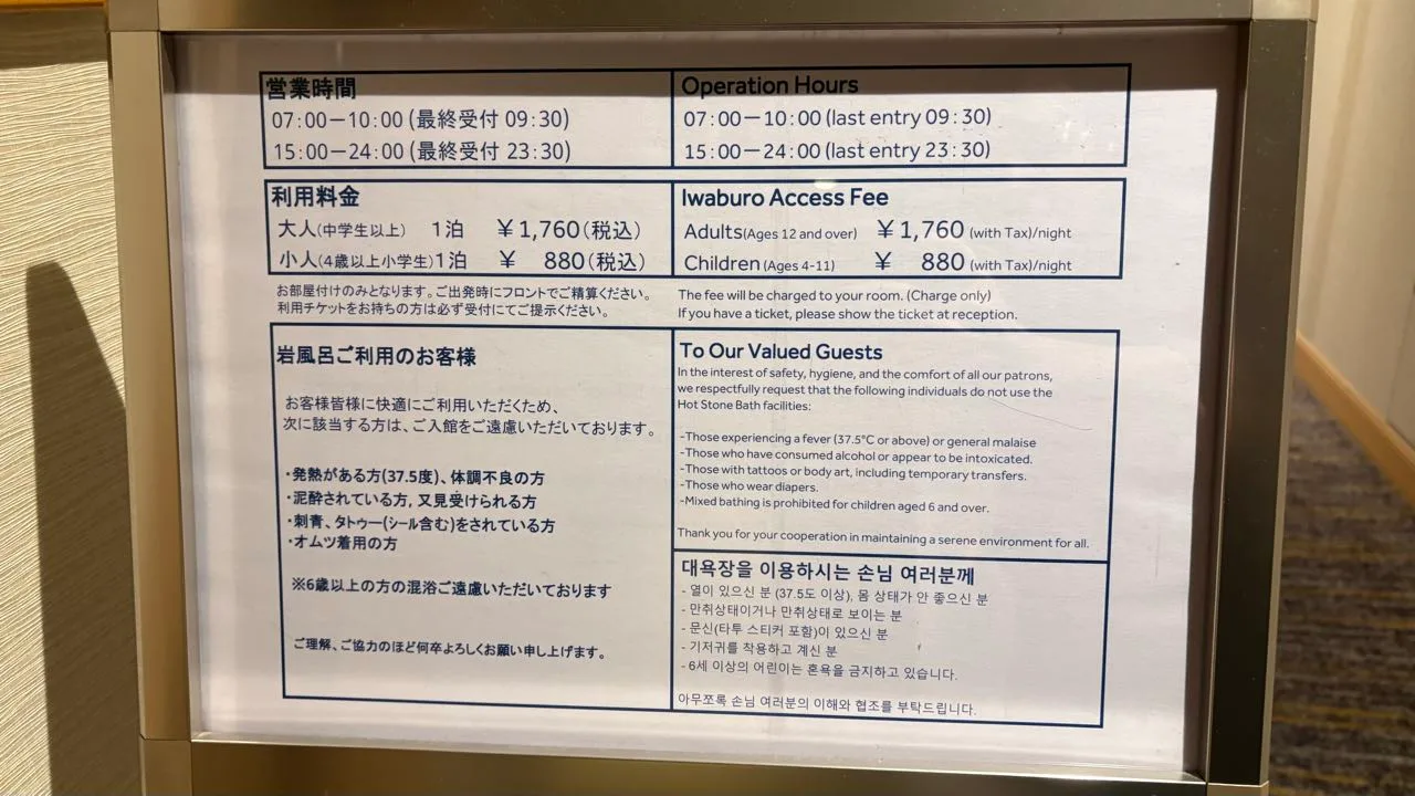 A framed bilingual notice listing operation hours 07:00 to 10:00 and 15:00 to 24:00, an Iwaburo access fee of 1,760 yen for adults and 880 yen for children, and a list of guests asked not to use the bath