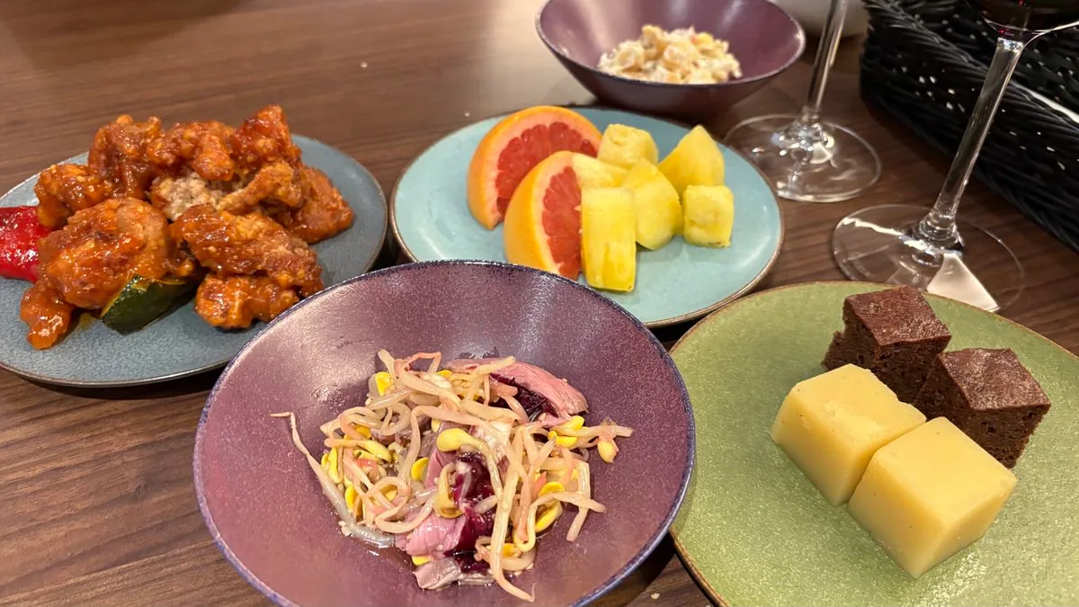 A later round in the lounge: fried chicken, beef and bean sprouts, fruit, cheese and wine glasses