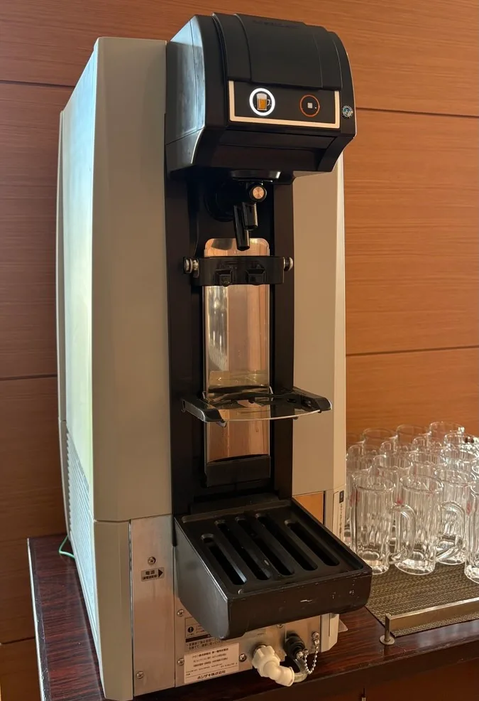 An automatic Orion draft beer machine on a wooden counter with rows of empty glass mugs