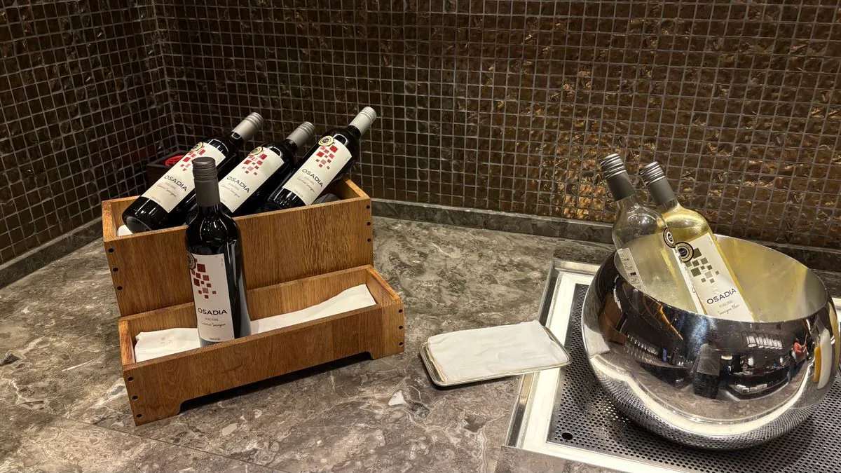 OSADIA red wine bottles in a wooden rack on a stone counter, with white bottles chilling in a metal ice bucket alongside