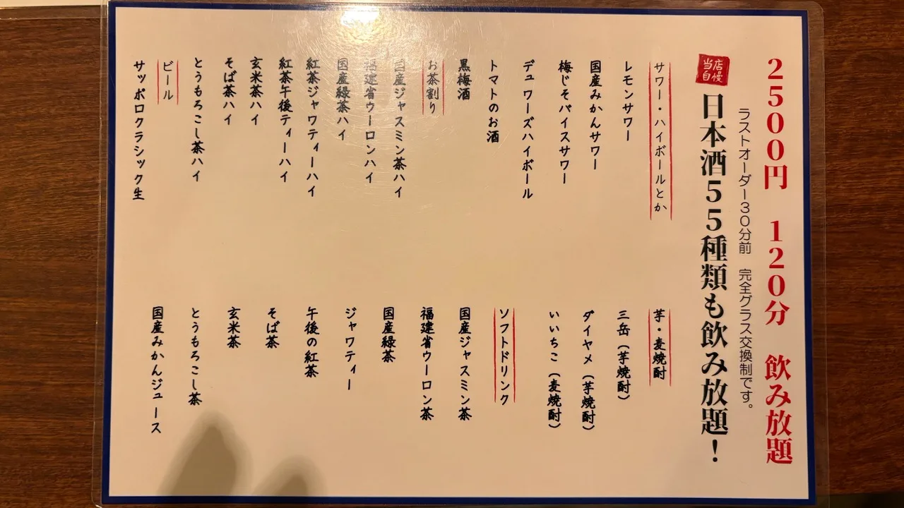 A laminated menu card on a wooden table, headed with the ¥2,500 120-minute all-you-can-drink plan