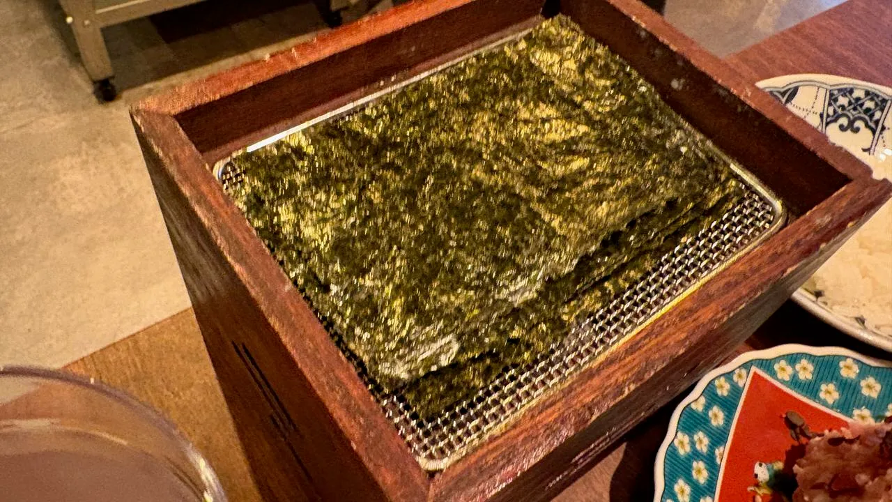 Sheets of nori seaweed inside a wooden box with a small flame burning underneath