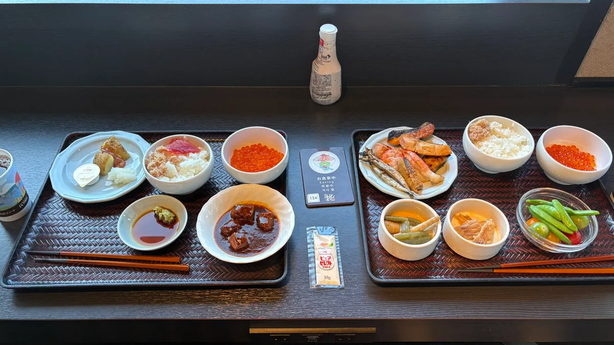 Two breakfast trays side by side, each with a small bowl of salmon roe and a bowl of rice topped with flaked crab