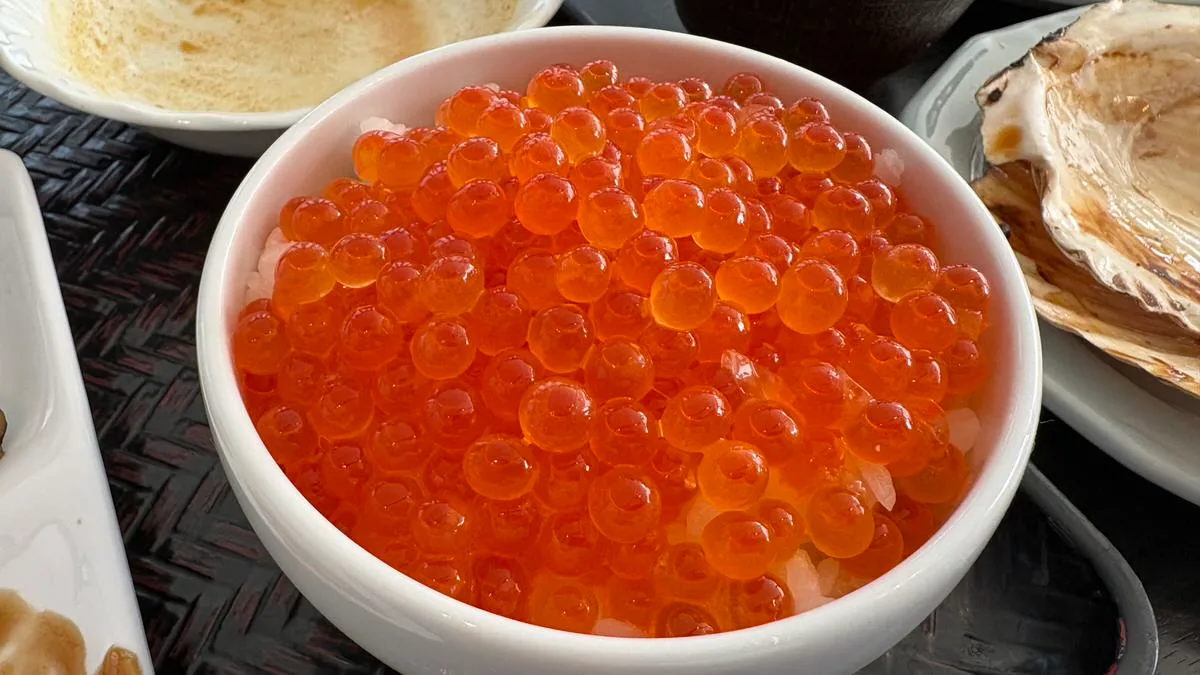 A bowl of rice buried under a thick layer of large orange salmon roe at a hotel breakfast buffet