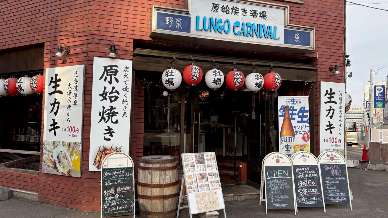 A red brick shopfront with a LUNGO CARNIVAL sign, red and white paper lanterns, tall vertical banners and chalkboards on the pavement