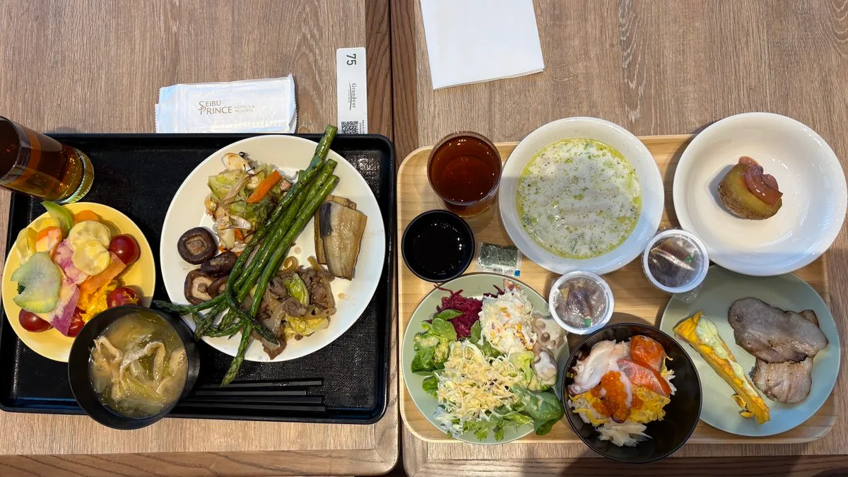Two breakfast trays, one each: grilled asparagus and shiitake, salad and fruit, miso soup, a small seafood rice bowl and grilled bacon