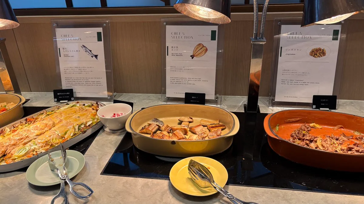 Three pans on the hot counter: salmon cooked with miso, grilled fish, and grilled lamb