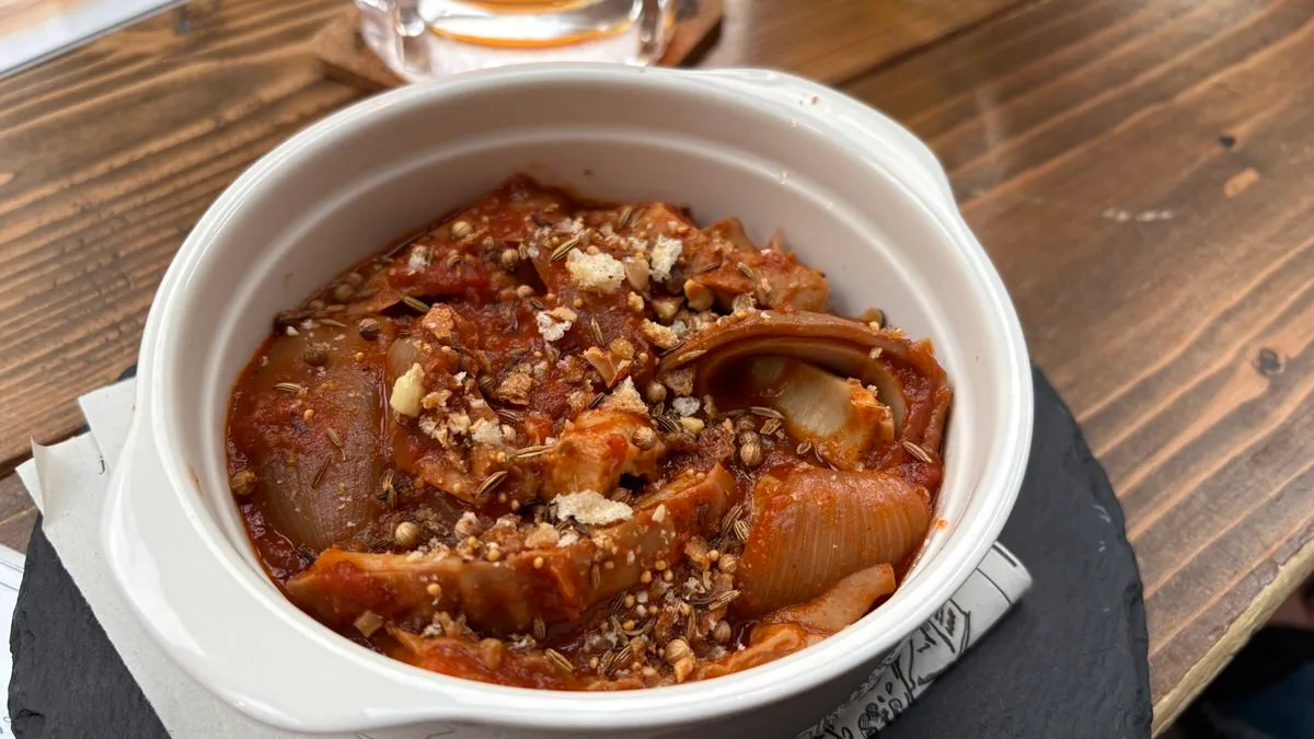 A dish of pork offal stewed in tomato with whole spices on top