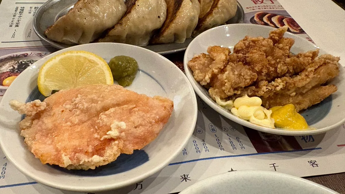 Two plates of fried chicken, one with a lemon slice and green paste, the other with mayonnaise and mustard