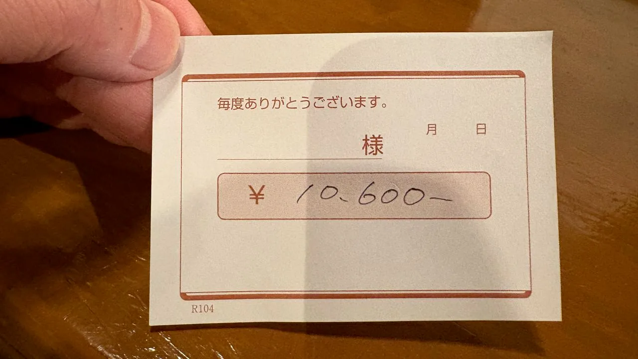 A small printed card held in a hand, with a total of 10,600 yen written by hand in the box